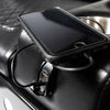 An iPhone being charged in the built-in USB ports on a black Comfort Before Pain Waiting Room Bench by TATSoul. 